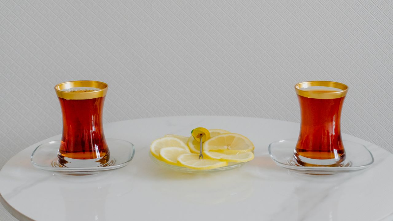 two tea glasses with lemons on a white marble table in a minimalist se