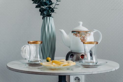 Free A sophisticated tea set arrangement with lemons, glass cups, and decorative vase on a marble table. Stock Photo