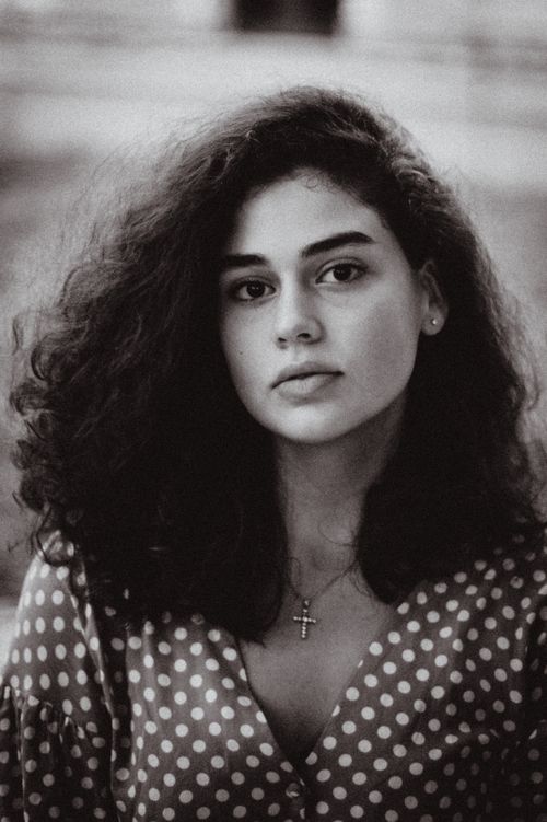 Free Timeless black and white portrait capturing the essence of a young woman with natural curls and serene gaze. Stock Photo