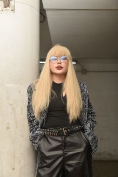 Stylish woman with sunglasses and blonde hair in an urban indoor environment.