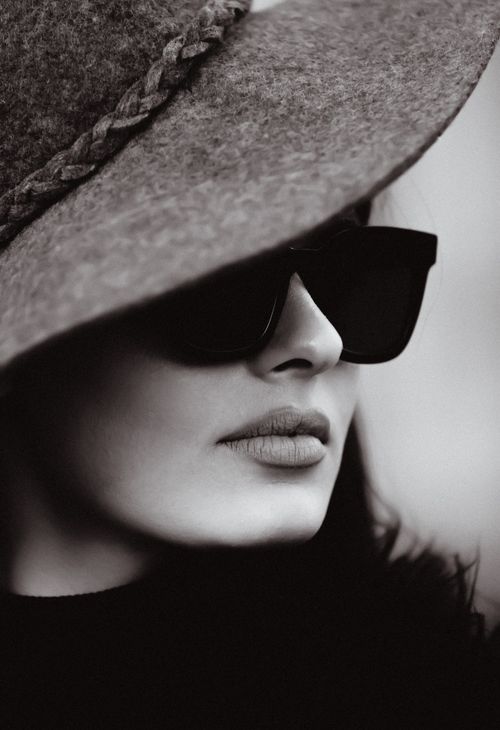 Free Stylish monochrome portrait of a woman wearing sunglasses and a hat, showcasing elegance and fashion. Stock Photo