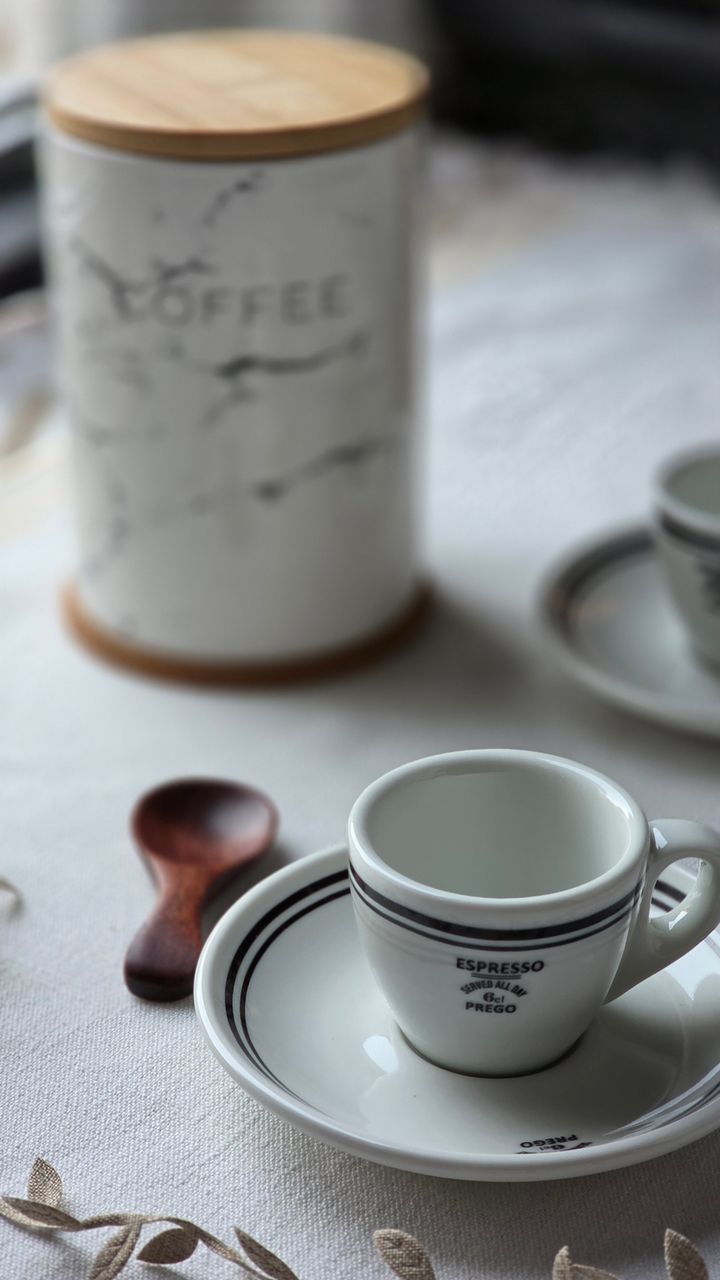 Matching glass coffee canisters arranged on an open shelf of a coffee bar hutch
