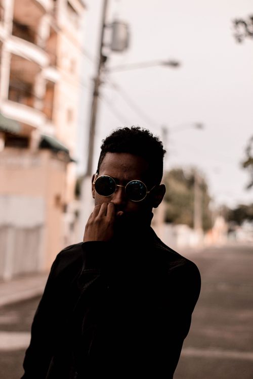 Free Stylish male model with glasses posing on an urban street in daylight, showcasing fashion and style. Stock Photo