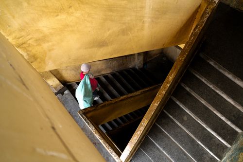 Free A person descends an urban stairwell in Vietnam, showcasing architectural patterns and worn textures. Stock Photo