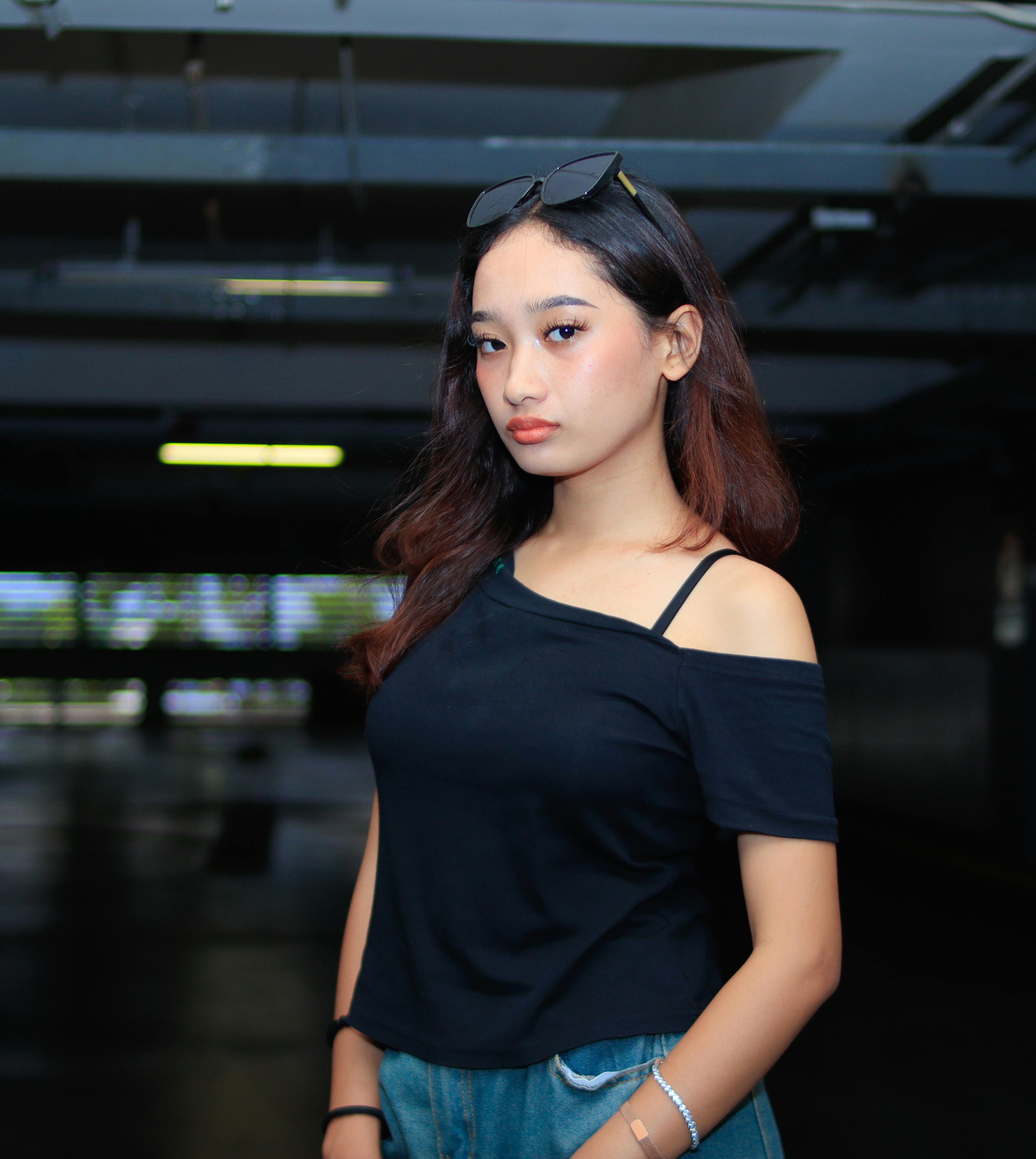 Portrait of a young woman wearing a stylish outfit indoors with a confident look and dark background.