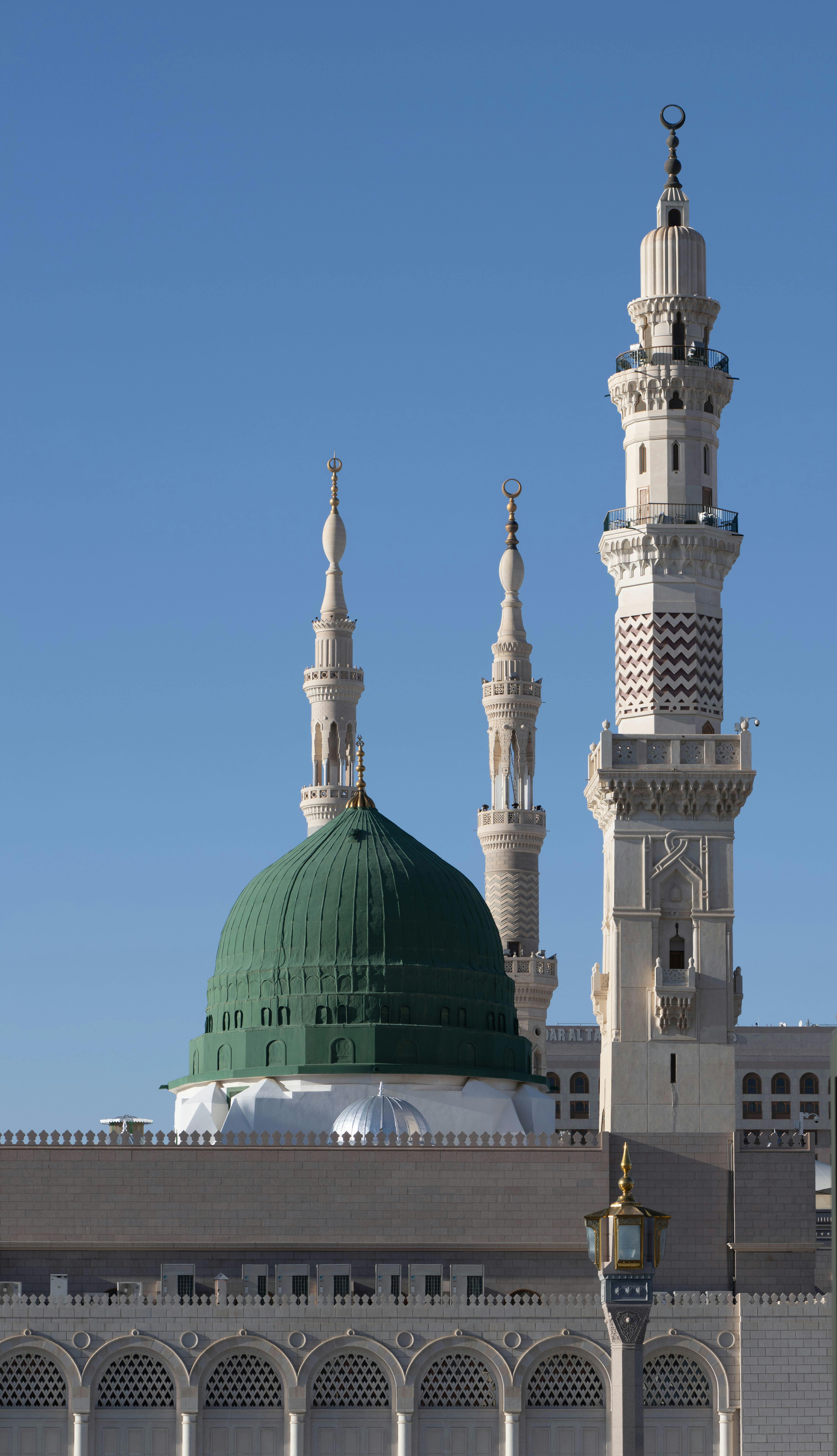 Elegant view of the Green Dome and minarets of Al-Masjid an-Nabawi against a clear blue sky.