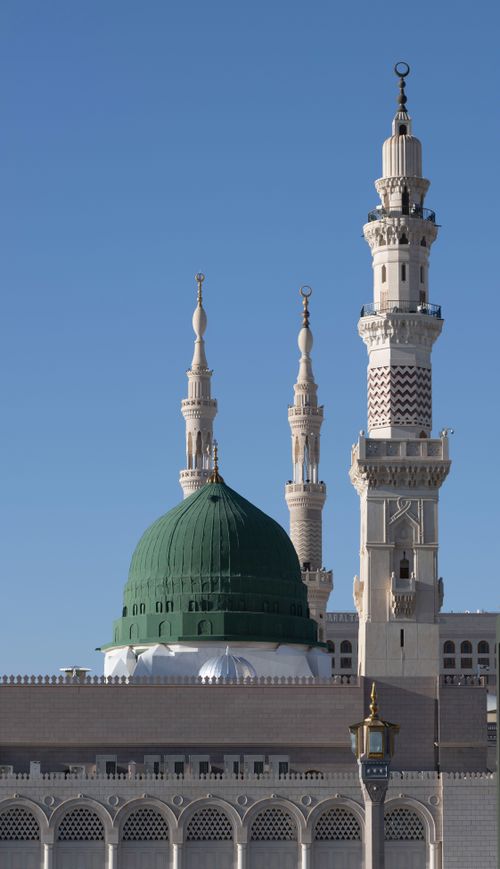Free Elegant view of the Green Dome and minarets of Al-Masjid an-Nabawi against a clear blue sky. Stock Photo