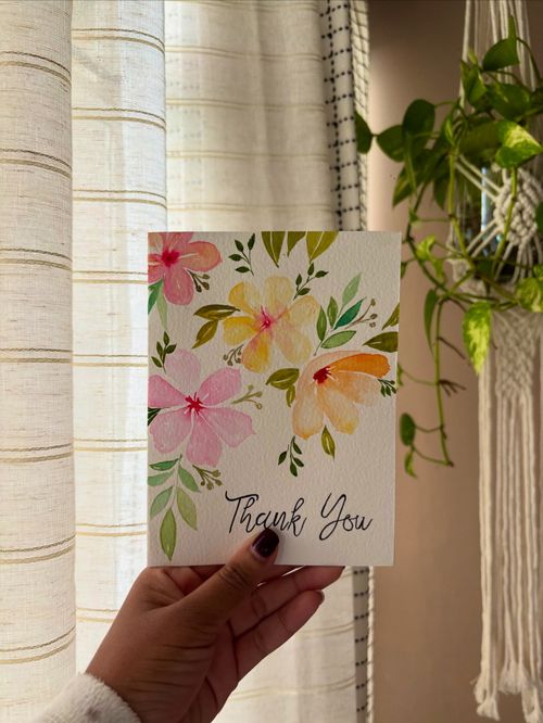 Free A hand holding a floral thank you card against a softly lit background. Stock Photo