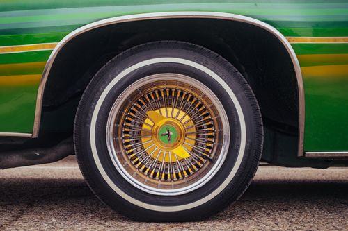 Free Detailed shot of a vintage car wheel with vibrant green and yellow colors. Stock Photo