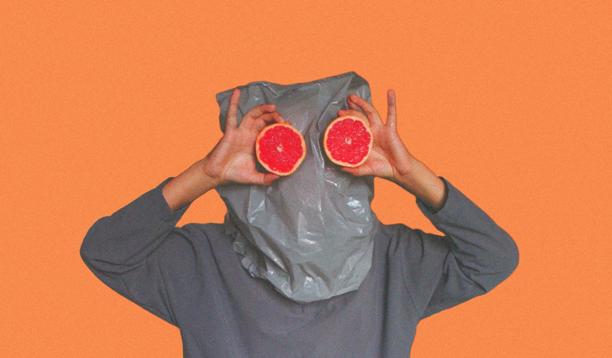Free Person Covered With Plastic Bag on Head While Holding Sliced Blood Orange Stock Photo