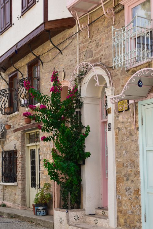Free Beautiful stone facade in an old town setting with vibrant bougainvillea and pastel accents. Stock Photo