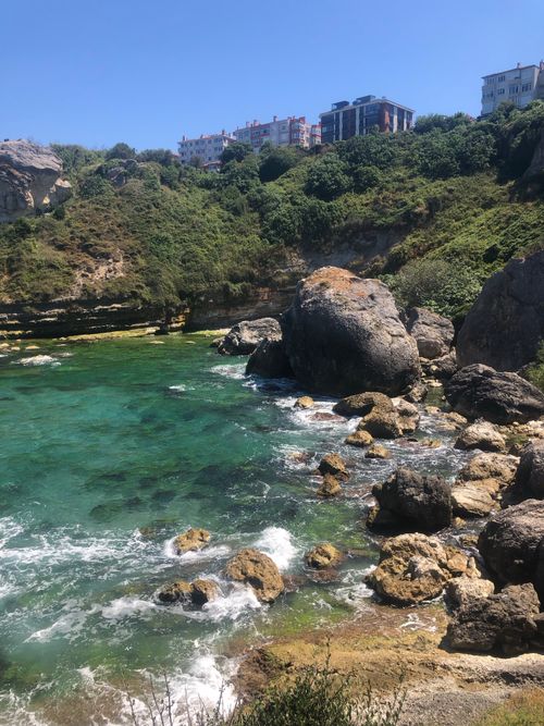 Free Beautiful rocky coastline with turquoise water and lush greenery under a clear blue sky. Stock Photo