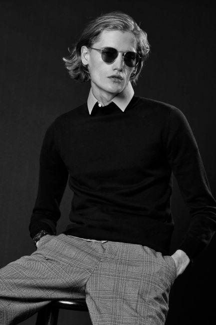Stylish black and white portrait of a man wearing sunglasses and fashionable attire.