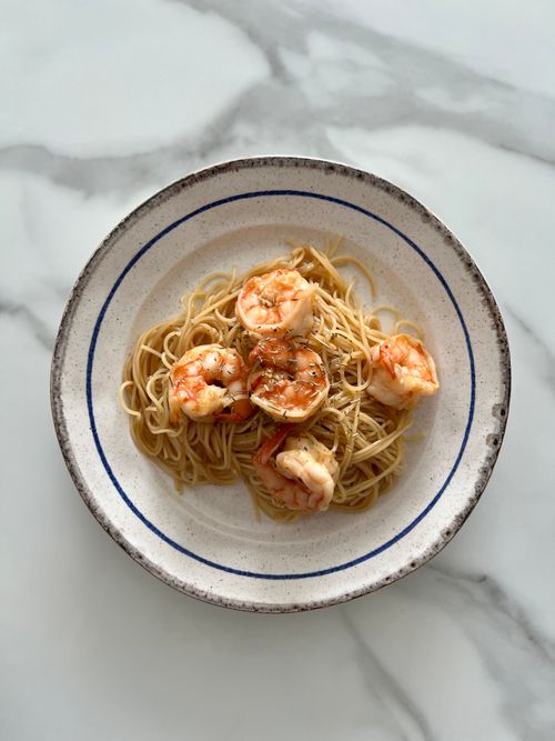 Free Delicious shrimp pasta served in a ceramic bowl on a marble surface. Stock Photo