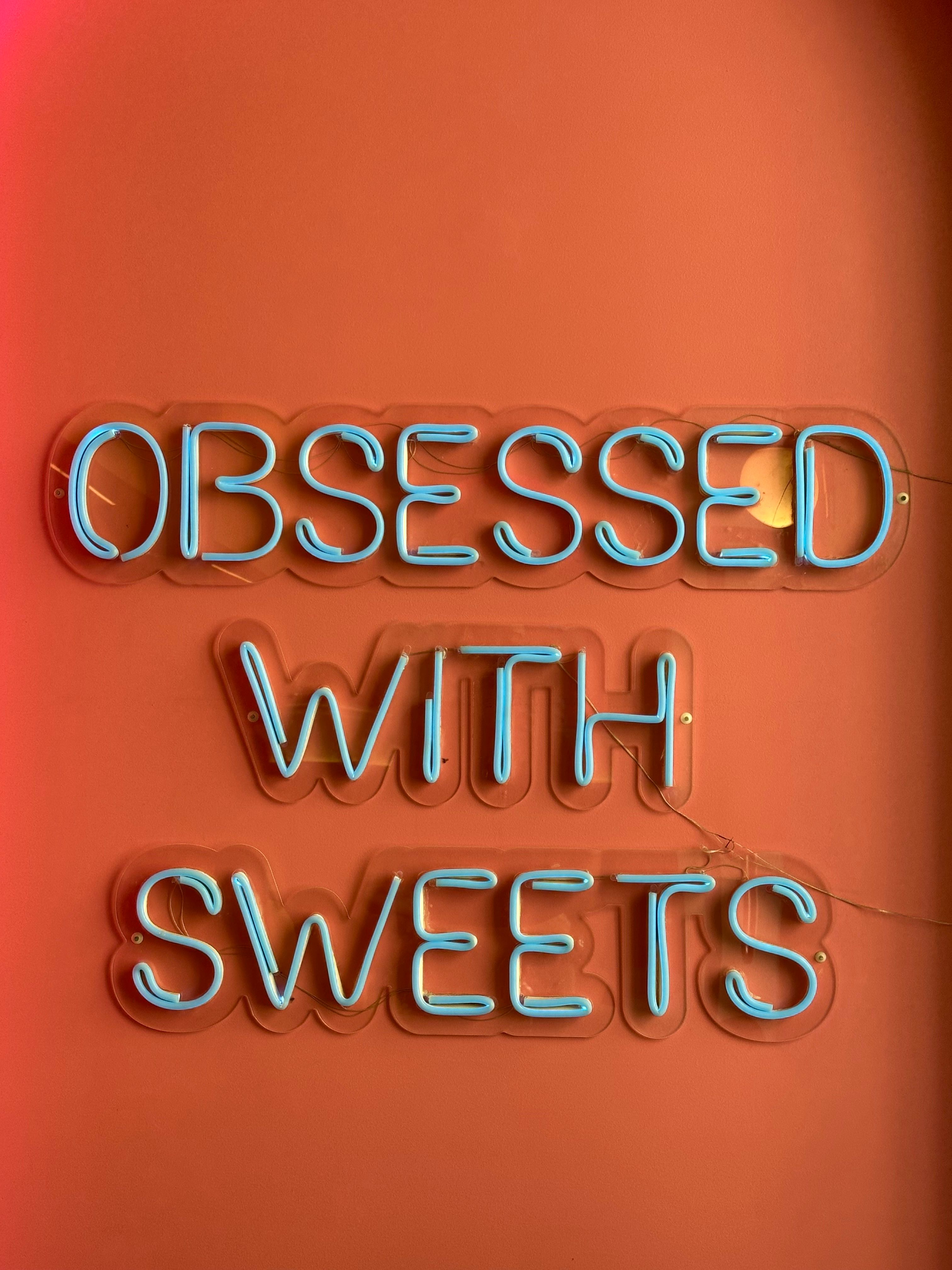 Neon Sign Reading 'Obsessed with Sweets' · Free Stock Photo