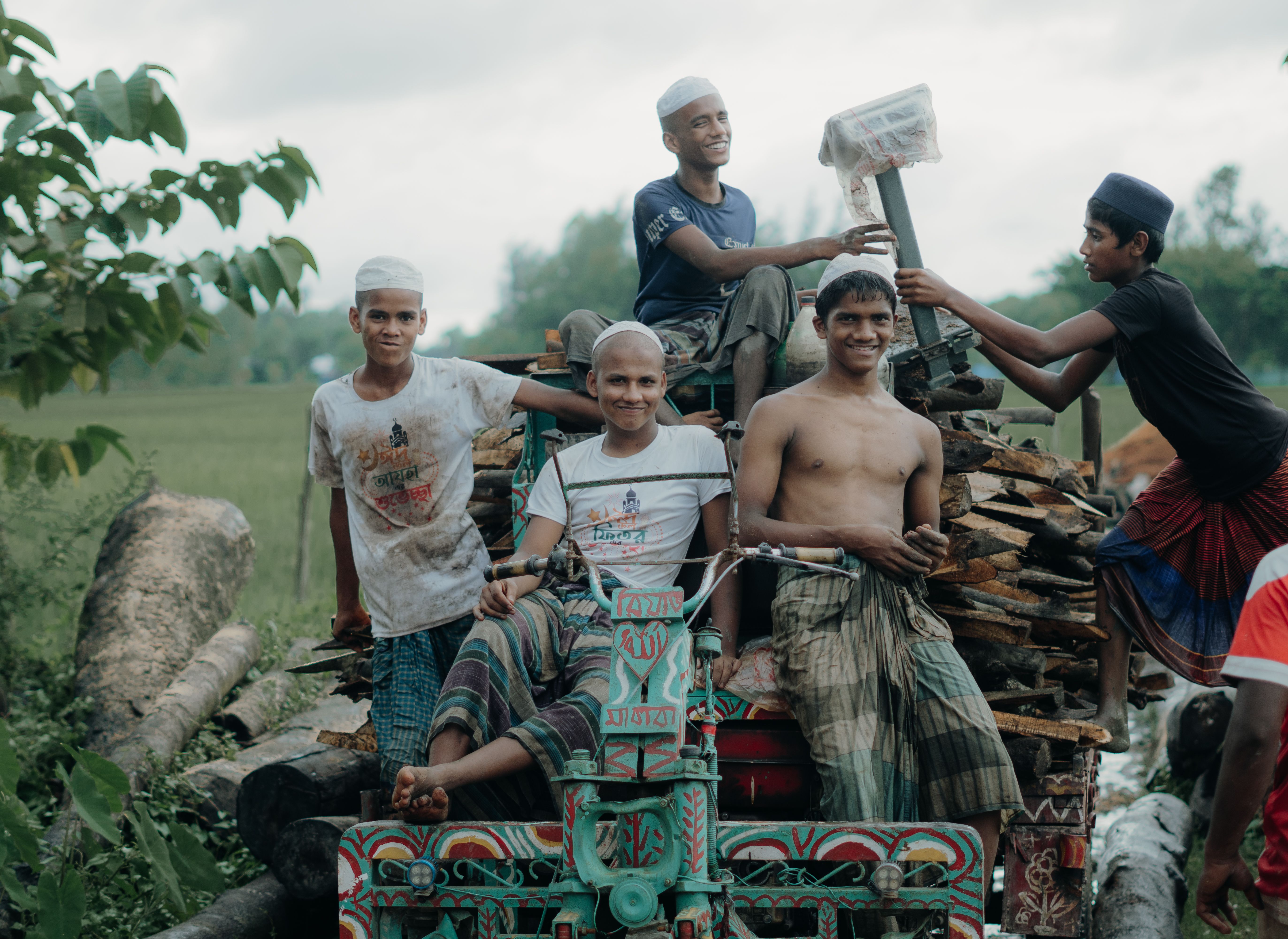 Cheerful boys riding on a colorfully decorated vehicle outdoors in a rural setting.