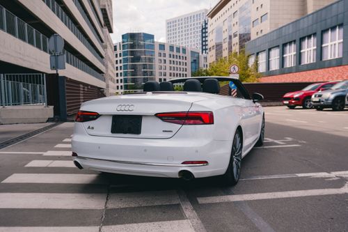 Free White convertible car in modern urban street of Kyiv, showcasing sleek design and city architecture. Stock Photo