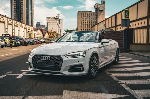 Free Stylish white convertible car parked on a city street in Kyiv, showcasing urban lifestyle and architecture. Stock Photo