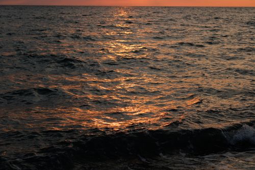Free Golden sunlight reflecting on calm ocean waves during sunset, serene and peaceful. Stock Photo