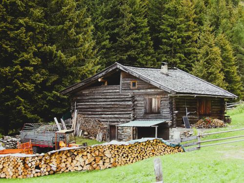 Free Charming log cabin nestled in Trentino forest with stacked firewood. Stock Photo