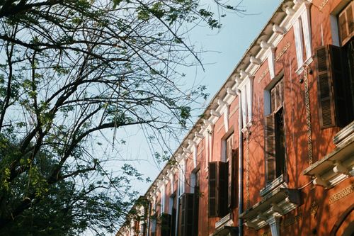 Free Warm sunlight illuminating colonial-style architecture with intricate details and surrounding trees. Stock Photo