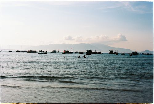 Free Calm waters with fishing boats at sunrise, scenic mountain view. Stock Photo