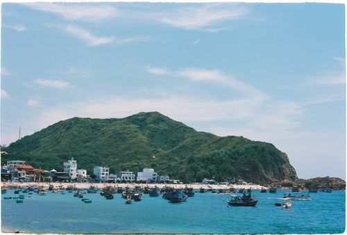 Free Serene coastal landscape featuring boats and lush green hills under a clear blue sky. Stock Photo