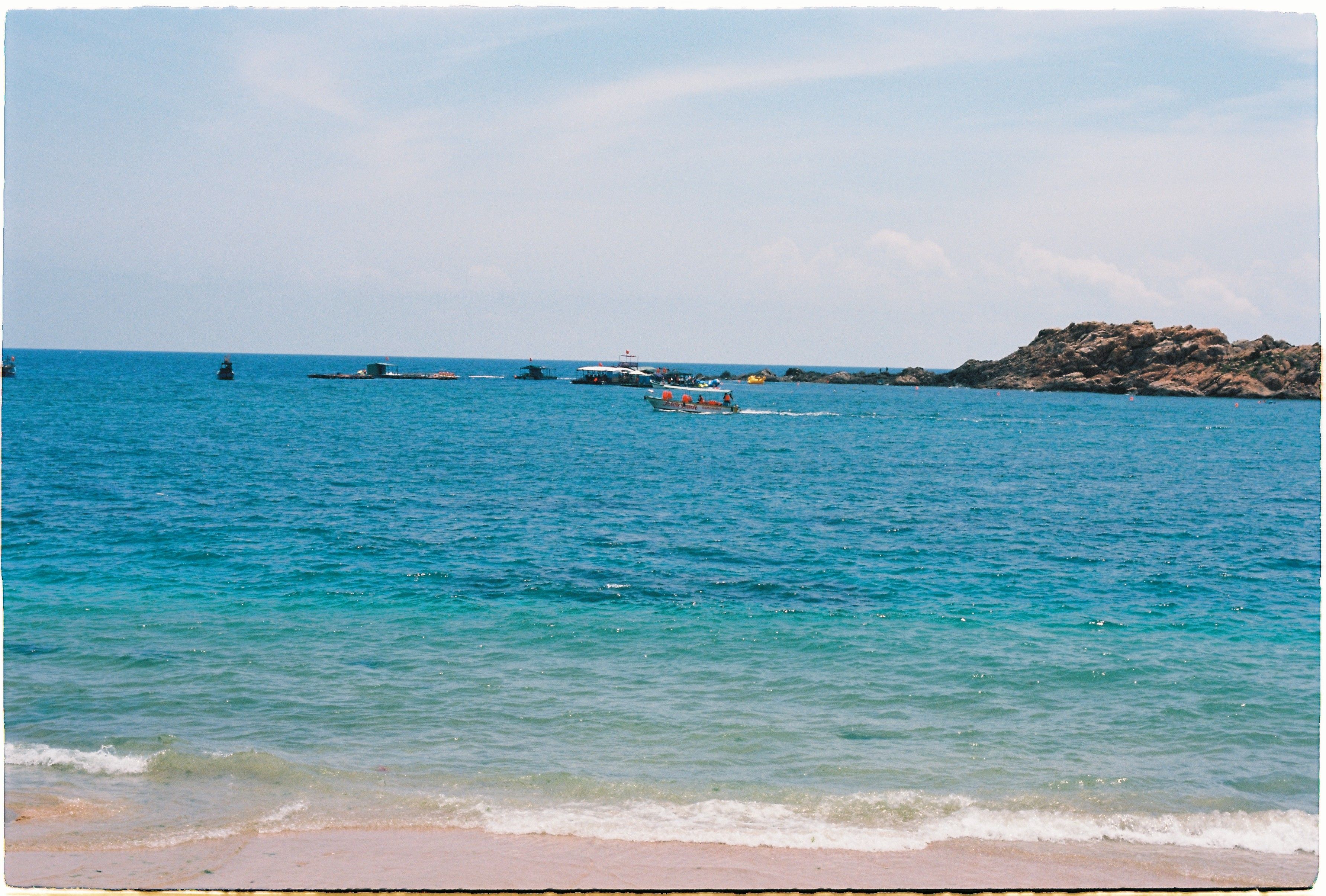 Vibrant Seascape with Boats and Rocky Coastline