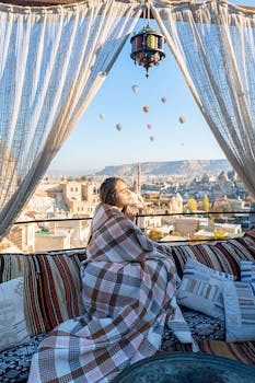 年轻女子在土耳其的阳台上欣赏风景，天空中飘着气球