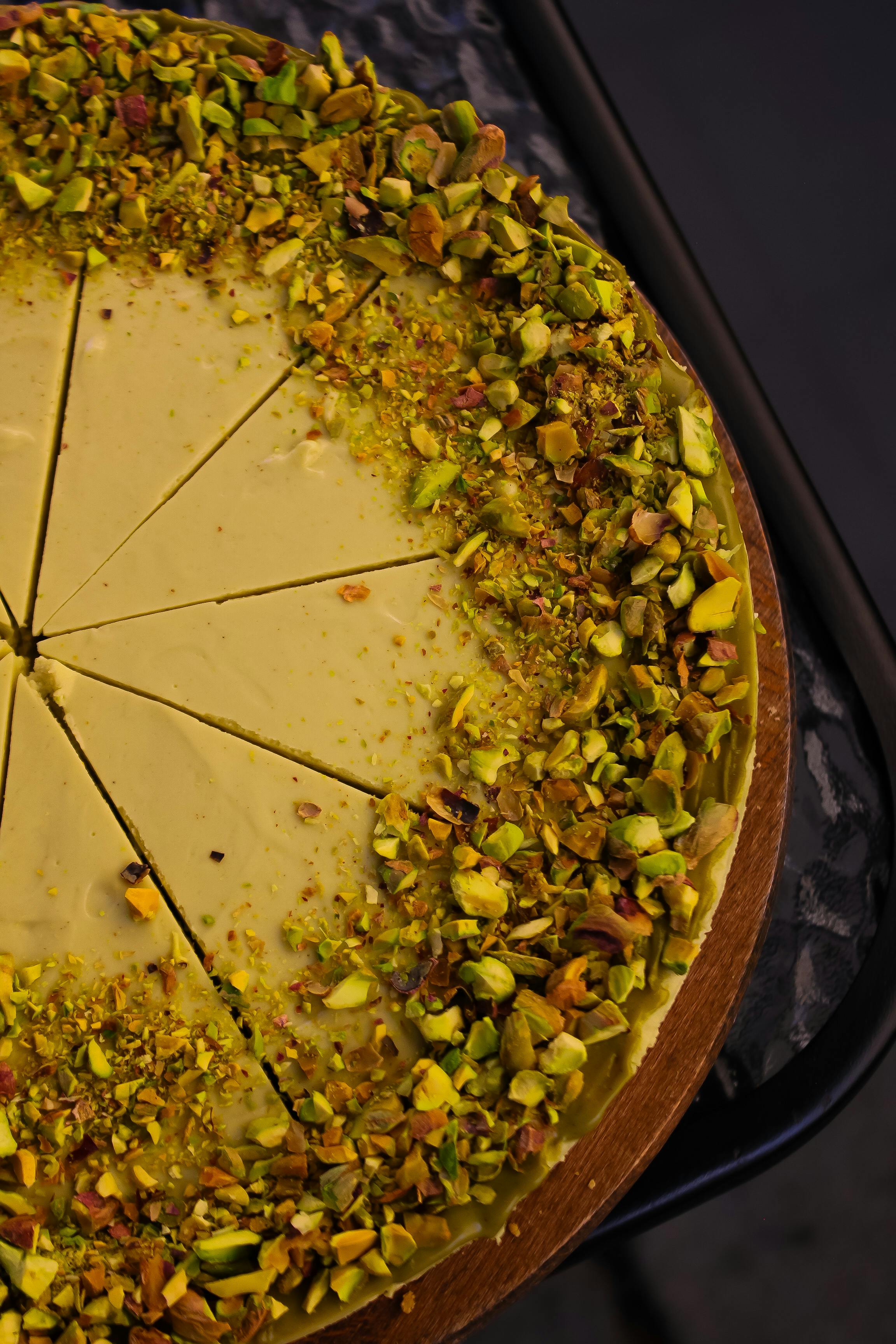 A close-up view of a sliced pistachio cake with golden crust and vibrant green nuts.