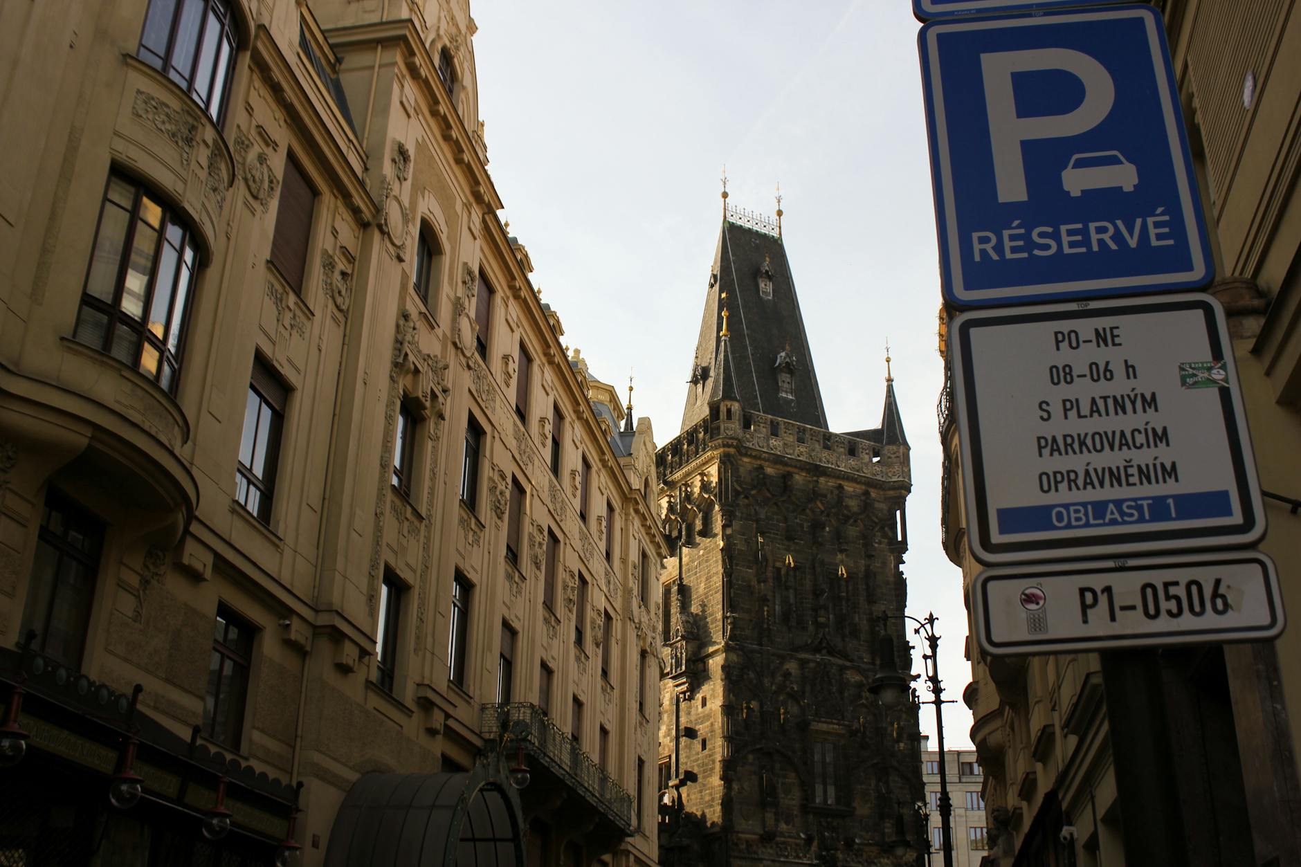 A charming Prague street scene featuring a historic Gothic tower and architectural details.