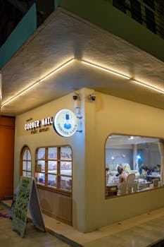 Nighttime view of a corner nail salon with visible interior activity.