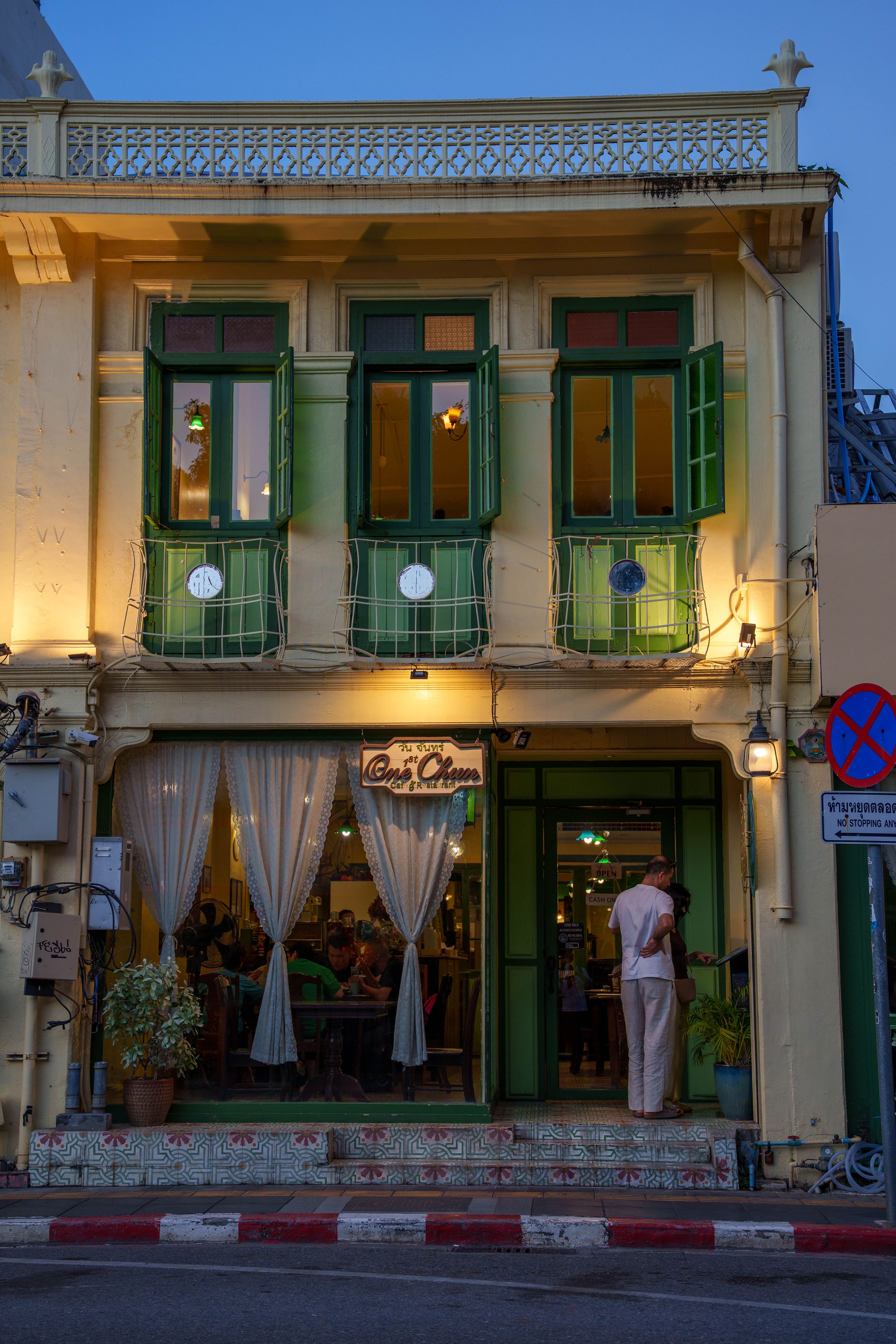 Cozy cafe with vibrant green windows, evening setting, soft lighting, and street view.