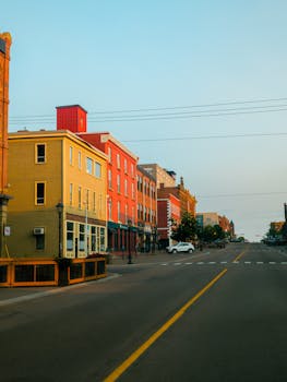 Vibrant downtown street with colorful buildings and empty road at sunset.