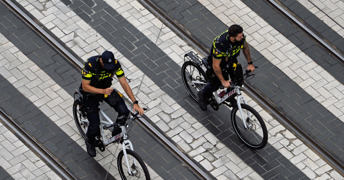 Photo by Martijn Stoof Two police officers on bicycles patrol a city street, highlighting urban law enforcement.