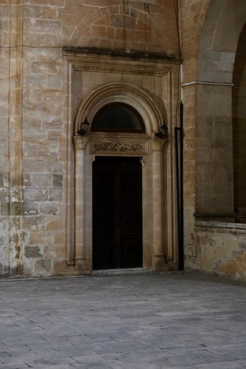 Free A historic stone archway door with ornate details and Arabic script on an ancient building. Stock Photo