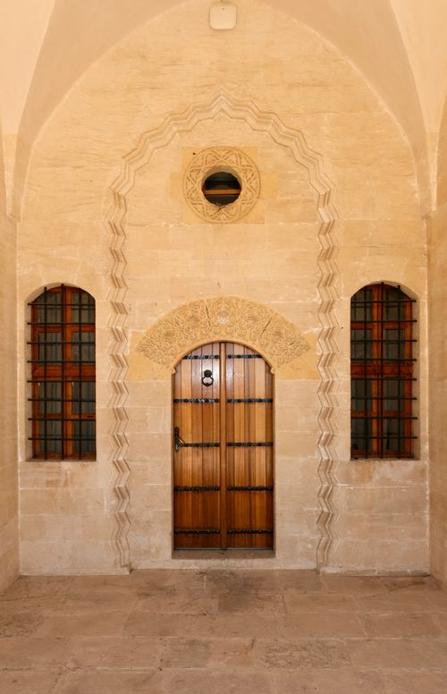 Free Elegant arched stone entrance featuring a traditional wooden door and symmetrical design. Stock Photo