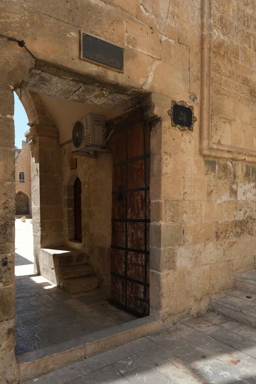 Free Explore an ancient stone entrance with rustic wooden door in a sunlit alley. Stock Photo