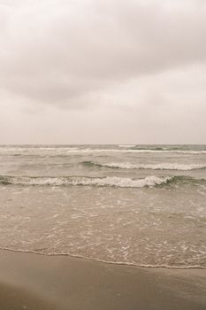 A calm, overcast day at the beach with gentle waves and a peaceful ambiance.