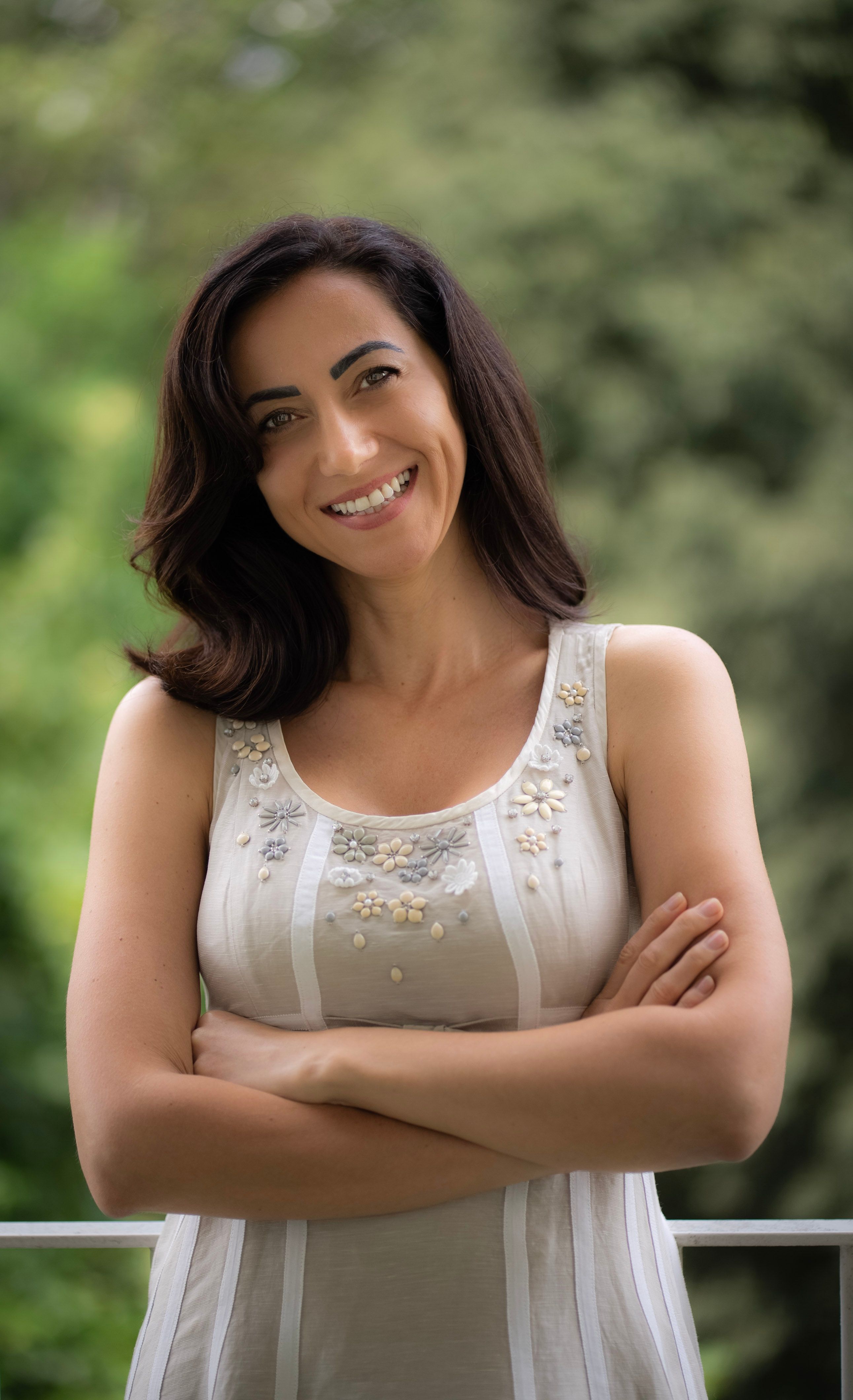 Smiling woman in Milan posing outdoors with crossed arms and confident expression.