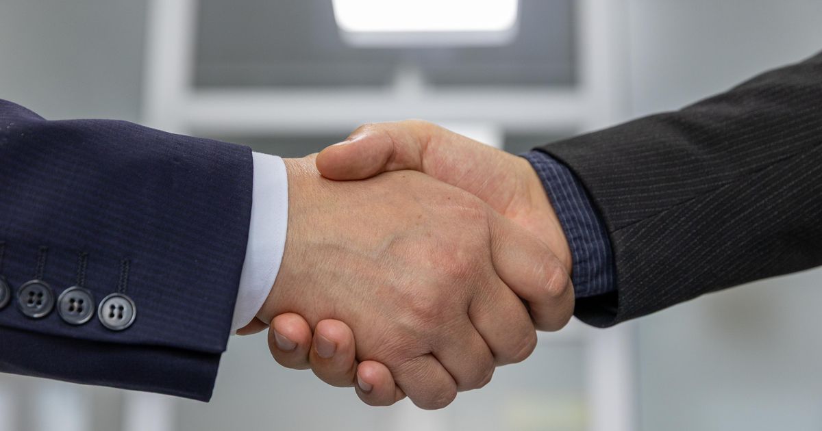 Zwei Geschäftspartner geben sich nach Vertragsunterzeichnung die Hand als Sinnbild für den Kauf einer Reinigungsfirma