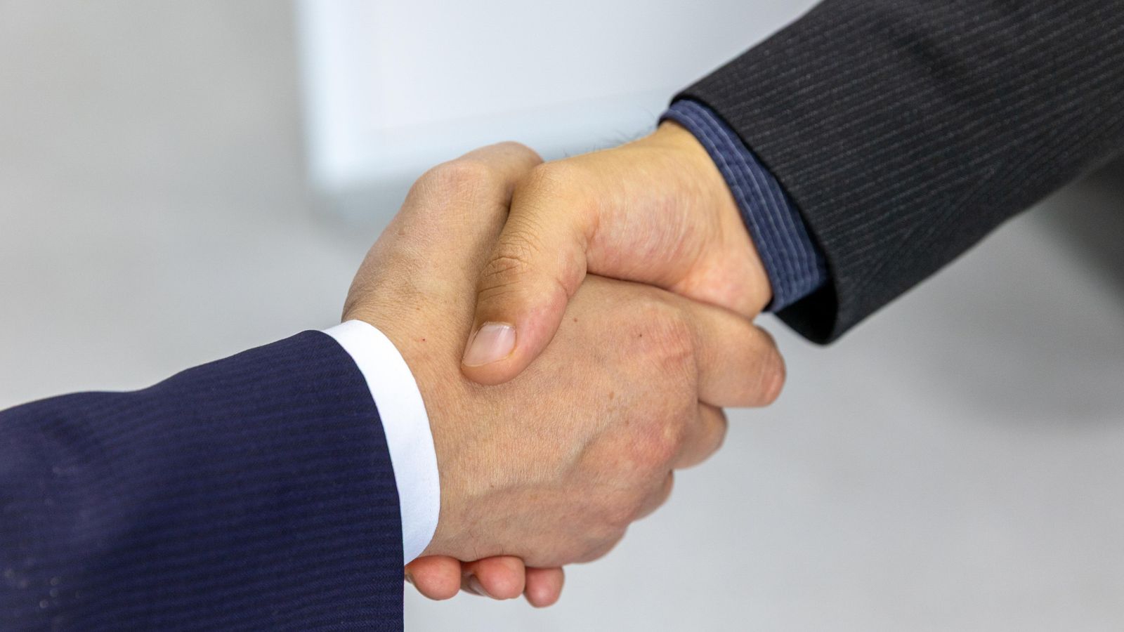 Close-up of two businessmen shaking hands, symbolizing agreement and partnership.