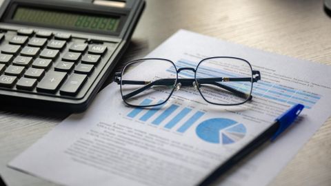 Financial document with a calculator, pen, and glasses symbolizing data analysis.