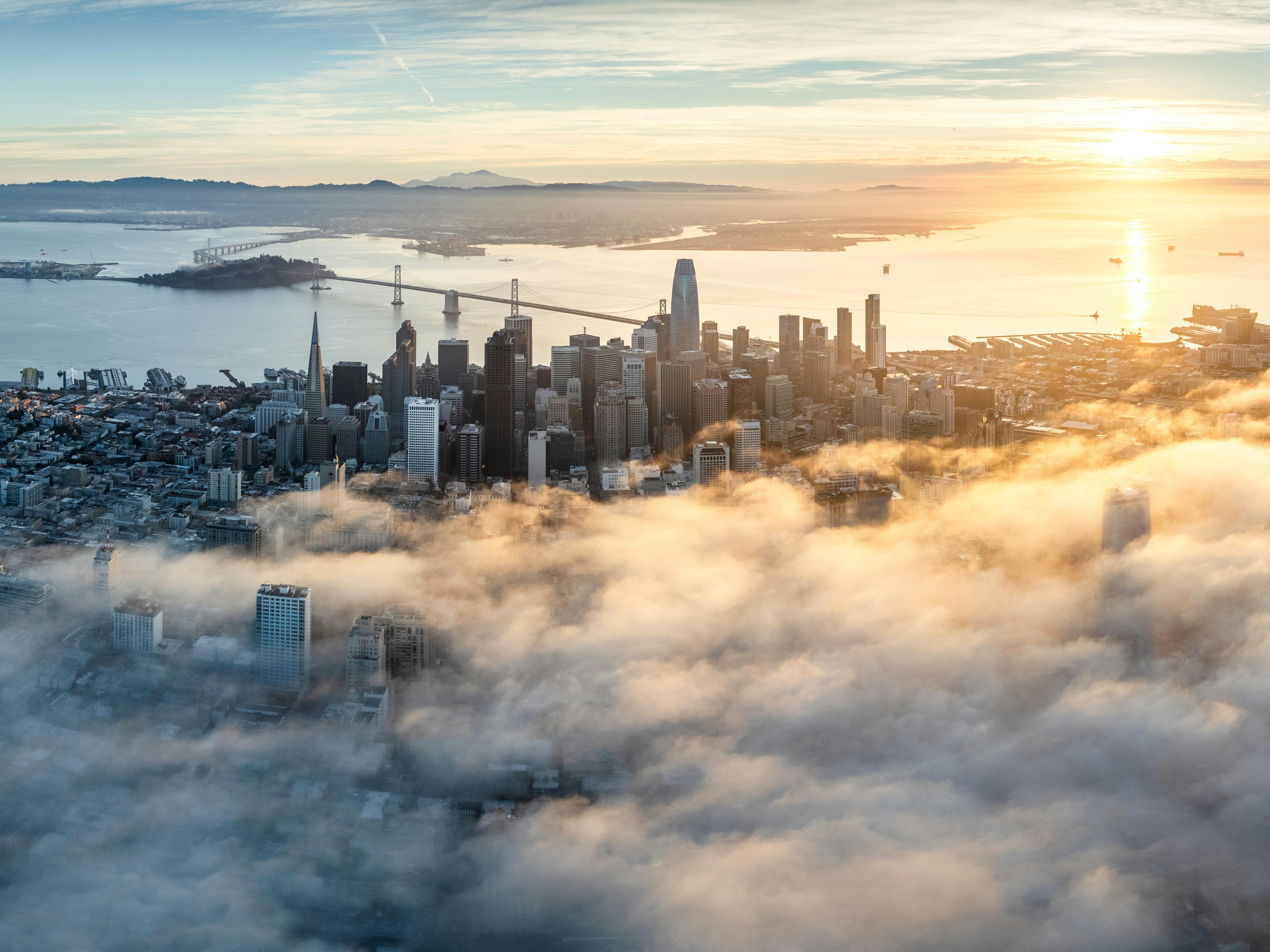 Enchanting aerial view of San Francisco skyline enveloped by morning fog at sunrise.