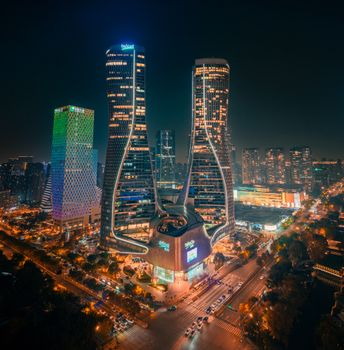A striking nighttime aerial view of a futuristic cityscape with illuminated skyscrapers and neon lights.