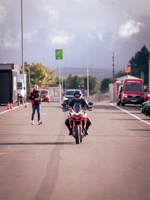 Free Motorcyclist in full gear riding along Nürburgring with clear sky. Stock Photo