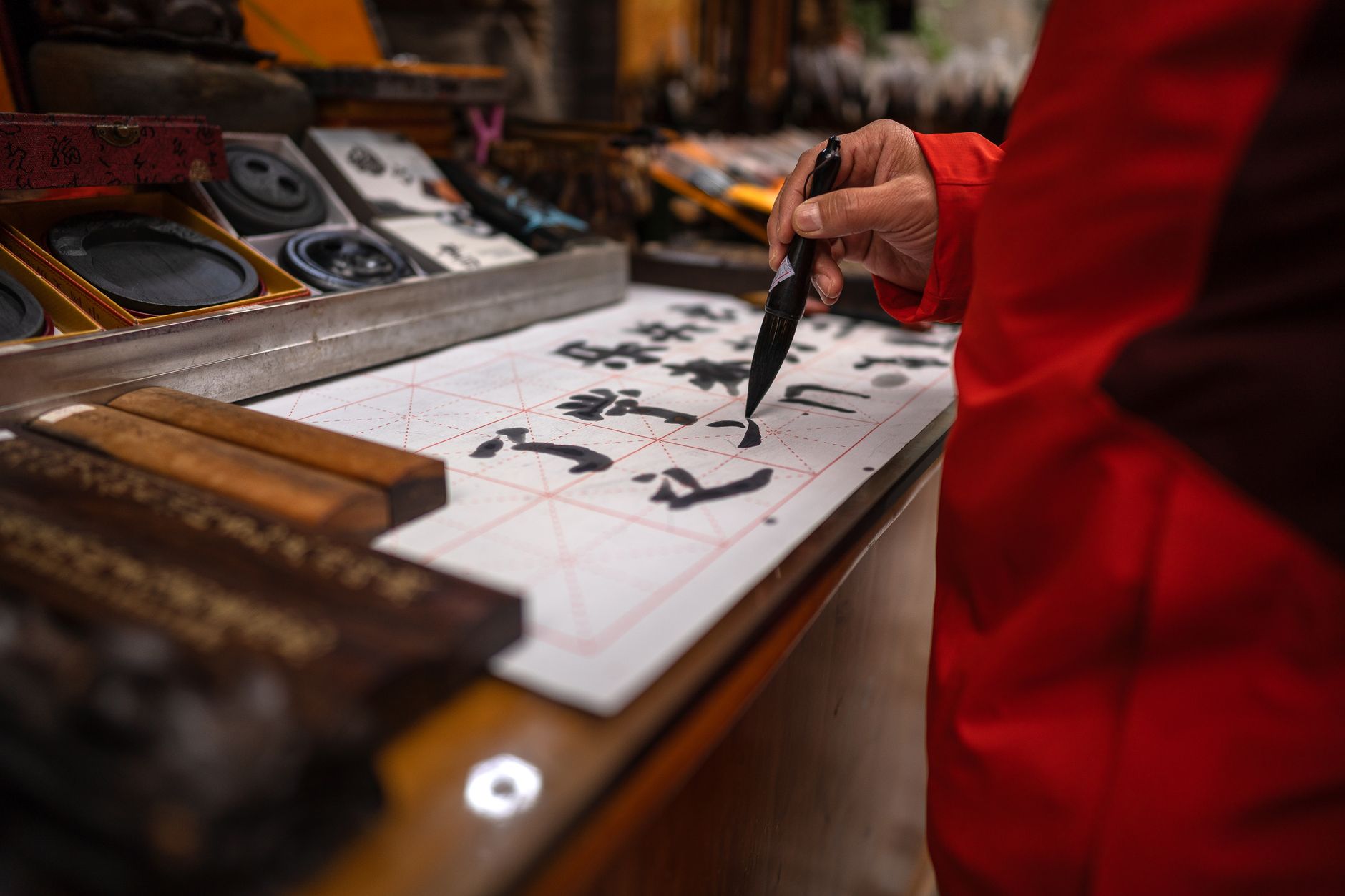 Close-up of person practicing traditional Chinese calligraphy with brush and ink.