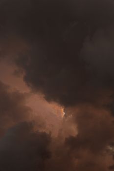 Moody dark clouds with a soft glow breaking through, hinting at a stormy atmosphere.