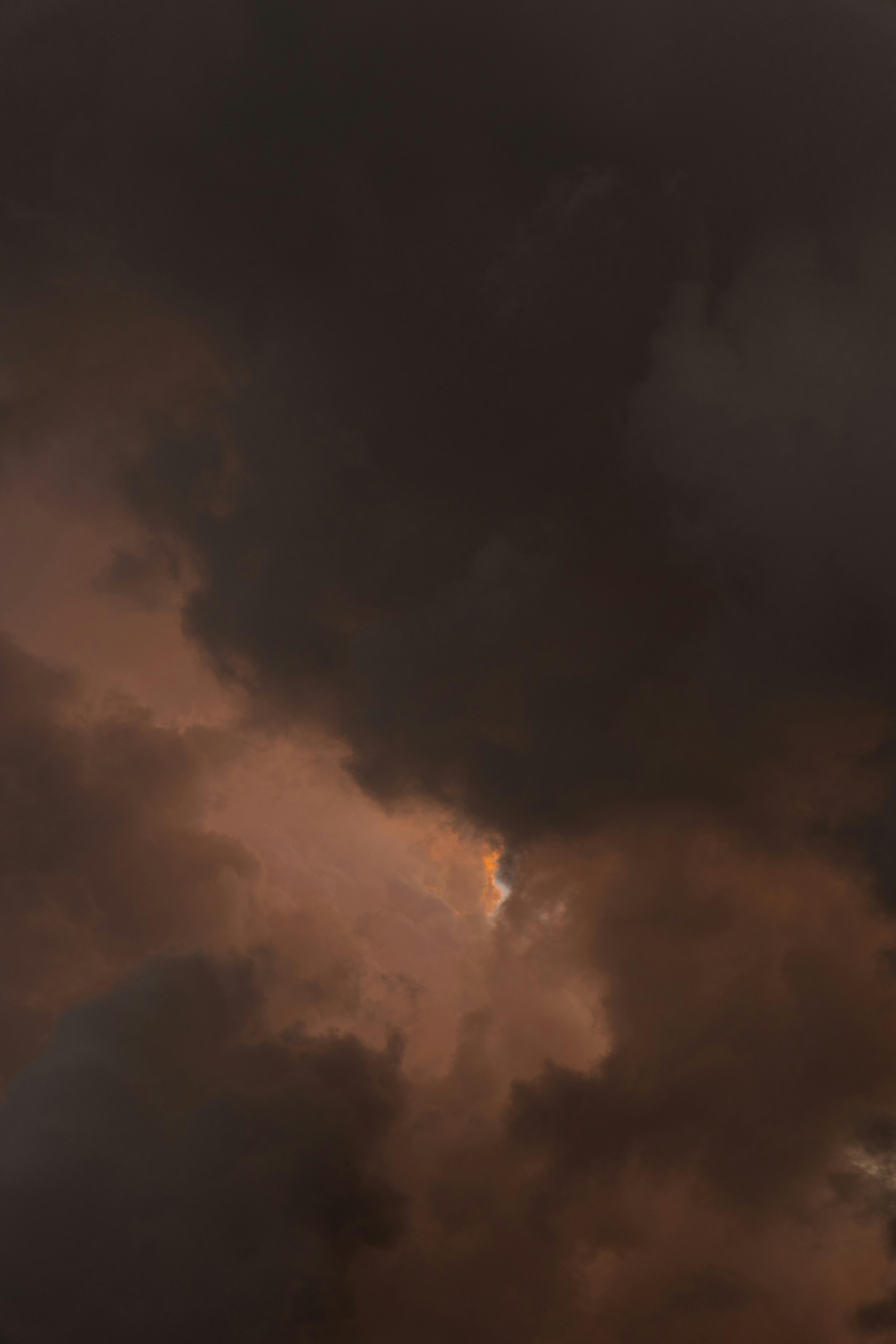 Gratis Stemningsfulde mørke skyer med et blødt skær, der bryder igennem og antyder en stormfuld atmosfære. Lagerfoto