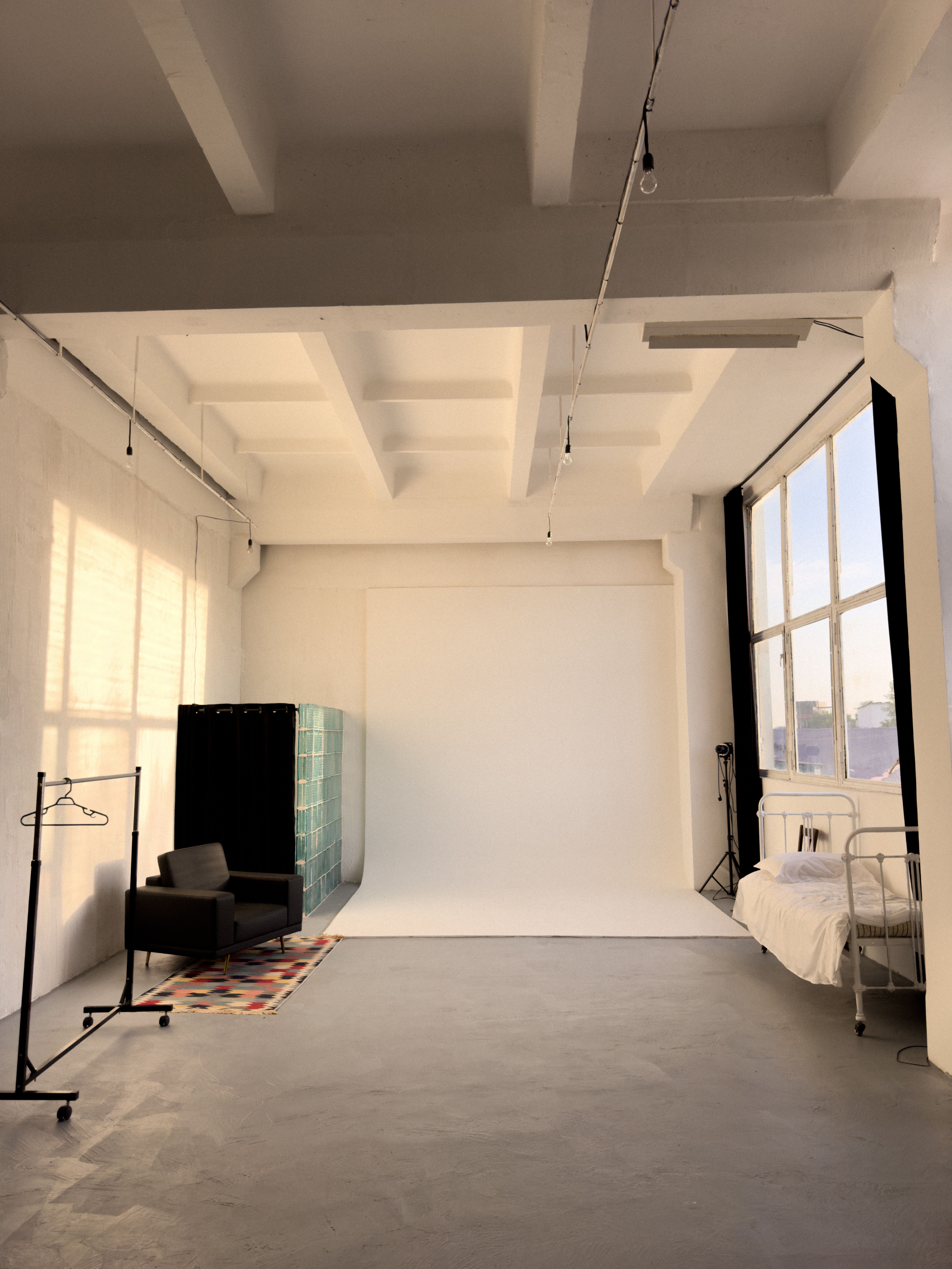 Sunlit minimalist studio with large windows and classic decor.